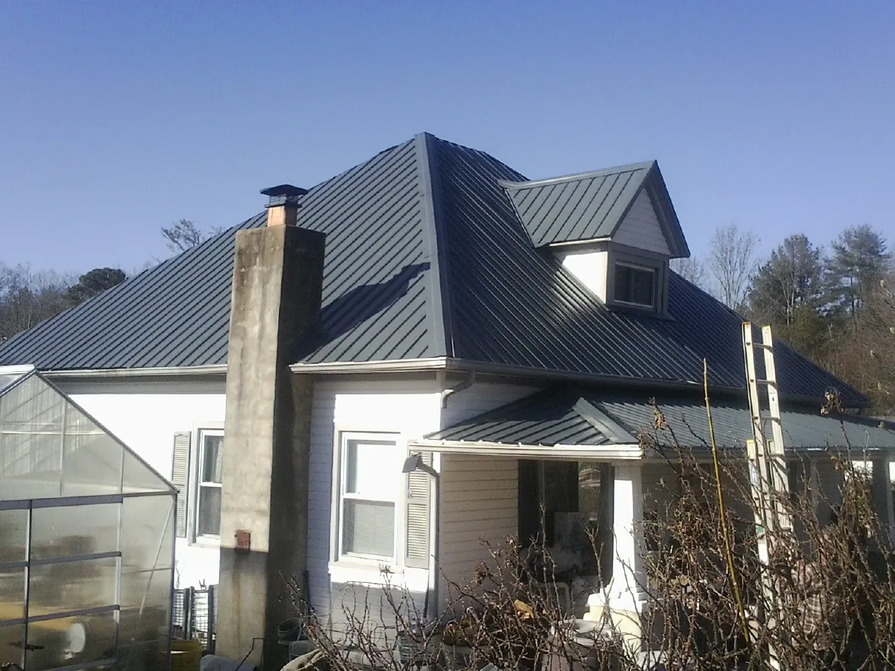 Dark blue standing seam metal roof on a white farmhouse with dormer — Slate & Tile Roof Repair by Roofing Brothers in Cross Fork