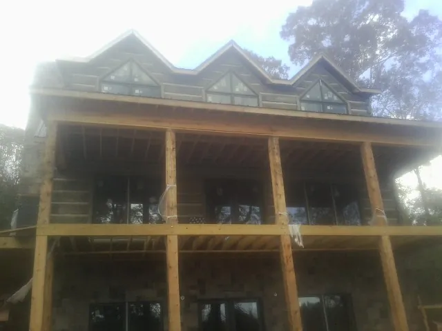 Dormers and porch framing on a large log home under construction — Roof Coating work by our crew in Cross Fork