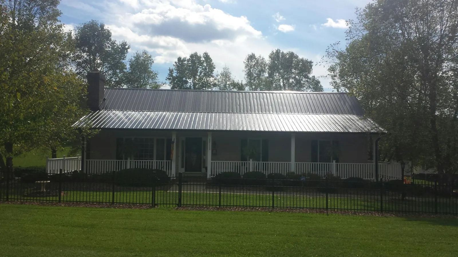 Gray metal roof on a brick ranch with a full width front porch — Gutter Guard Installation work by our crew in Cross Fork