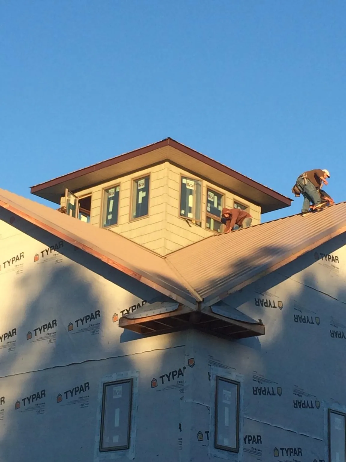 Roofers working around a rooftop cupola on a new metal roof at sunset — Roof Waterproofing in Cross Fork by Roofing Brothers